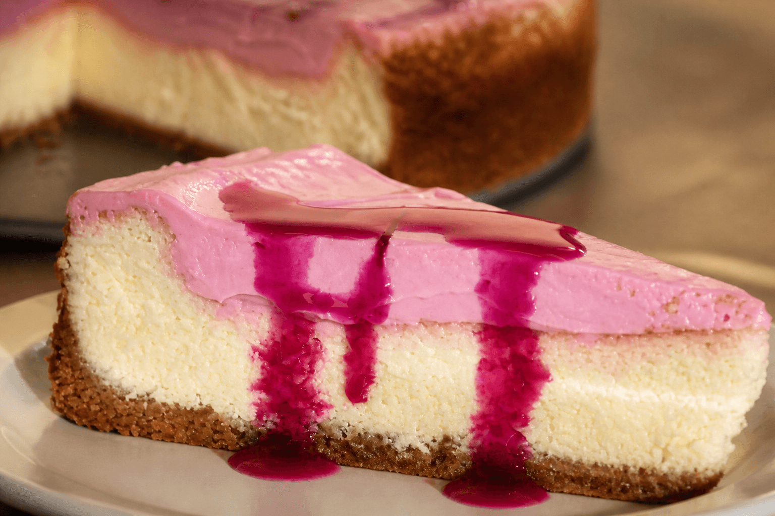 Close-up of creamy prickly pear cheesecake slice with vivid magenta topping and golden crust